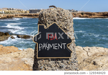 FDA Food and Drug Administration payment symbol. Concept words FDA payment on beautiful black chalk blackboard. Beautiful stone beach blue sea sky background. Business FDA payment concept. Copy space. 129348420