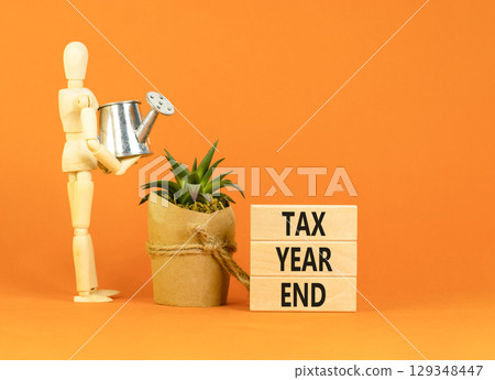 Tax year end symbol. Concept words Tax year end on beautiful wooden blocks. Beautiful orange background. Businessman model. Business tax year end concept. Copy space. 129348447