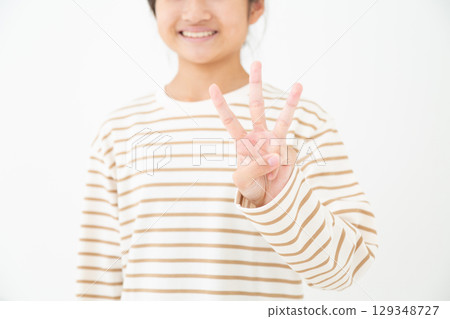 A middle school girl holding up three fingers A middle school girl holding up three fingers 129348727