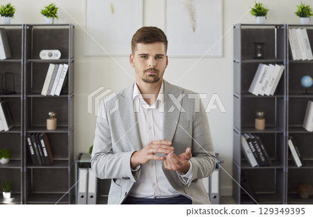 Portrait of serious businessman gesturing and looking at camera during formal conversation. 129349395