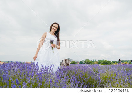 The lavender field envelops the sweet girl with its enchanting fragrance 129350488