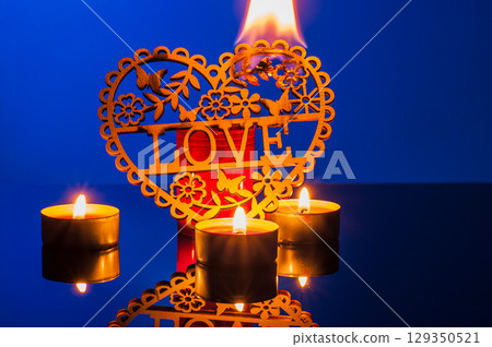 Lit candles on the deep blue backdrop create coziness and harmony Lit candles on the deep blue backdrop create coziness and harmony 129350521
