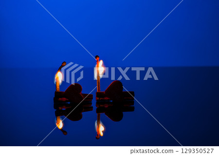 Two burning matches on a blue background 129350527