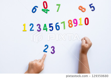 Child learning numbers with colorful wooden numerals on white background 129350680