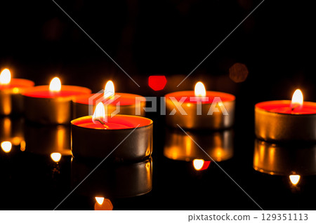 Candle flames tremble in the dark, creating a romantic mood Candle flames tremble in the dark, creating a romantic mood 129351113
