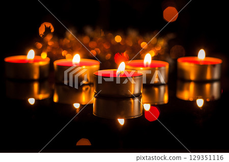 In the dark space, dozens of candles burn, giving off a gentle glow In the dark space, dozens of candles burn, giving off a gentle glow 129351116