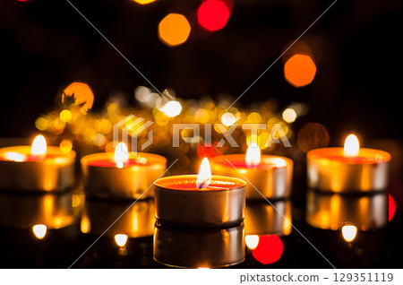 Dozens of candles shine like sparks of hope in the darkness 129351119