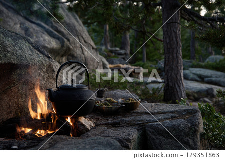 Campfire cooking with kettle in serene wilderness setting 129351863