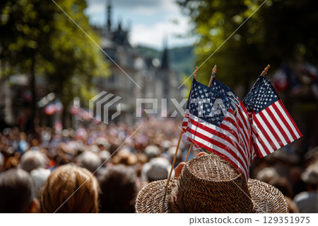 Crowd celebrating with flags during a sunny public event 129351975