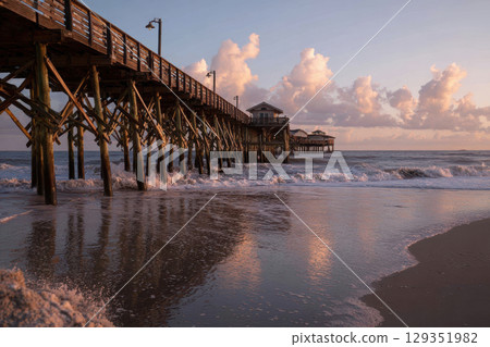 Rustic wooden pier extending into calm ocean waters at dusk 129351982