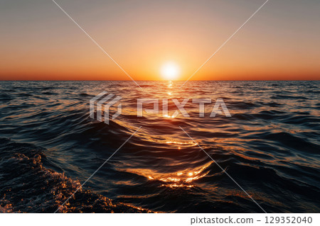 Golden sunset over tranquil ocean waves at horizon 129352040