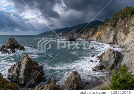 Rugged cliffs and ocean waves under a moody sky 129352046