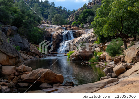 Waterfall cascading through rocky terrain in lush greenery 129352060