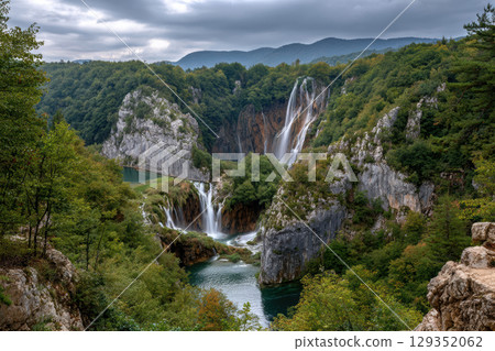 Majestic waterfall flowing through rocky cliffs in lush greenery Majestic waterfall flowing through rocky cliffs in lush greenery 129352062