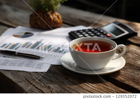 Economic research papers and tea on a wooden desk 129352072