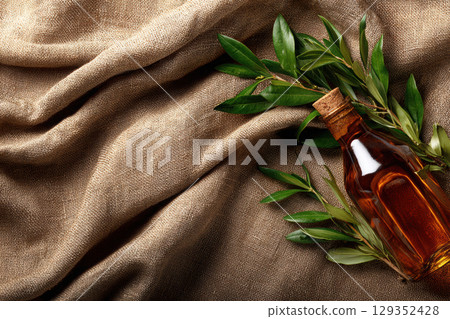 Olive oil bottle and fresh olive branches on rustic linen 129352428