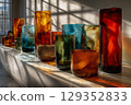 Translucent vases create colorful reflections on a white surface 129352833