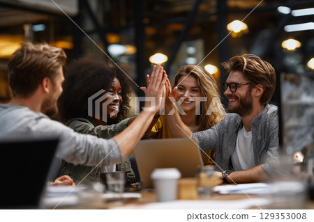Team celebrates success with high-fives in modern workspace 129353008