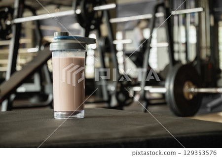 Protein shake bottle at gym. Fitness enthusiasm and post-workout routine. Healthy lifestyle and recovery after training. Close up. 129353576