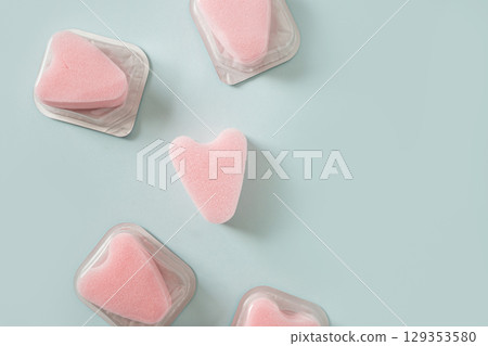 Set of female pink tampons stringless as heart in individual package on blue background. New generation. Hygiene accessories for women. View from above. 129353580