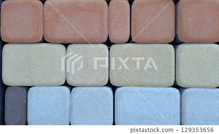 Patterned arrangement of multicolored concrete pavers in neat rows Patterned arrangement of multicolored concrete pavers in neat rows 129353656