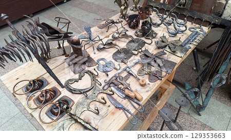 Assorted metal craftwork display on outdoor wooden table 129353663