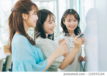 A female team having a meeting using a whiteboard A female team having a meeting using a whiteboard 129355184