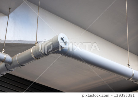 Grey air conditioning ducts and pipes hanging from a concrete ceiling Grey air conditioning ducts and pipes hanging from a concrete ceiling 129355381