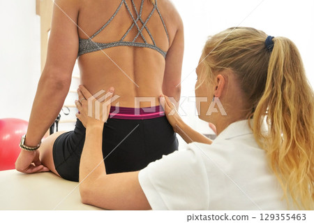 Woman patient at physiotherapy session, detail on therapist hands touching muscles on her back 129355463
