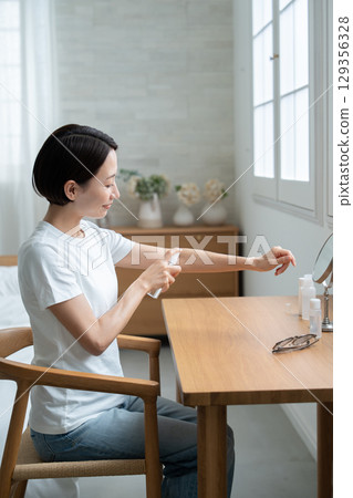 一位女士在手臂上塗抹防紫外線劑 一位女士在手臂上塗抹防紫外線劑 129356328