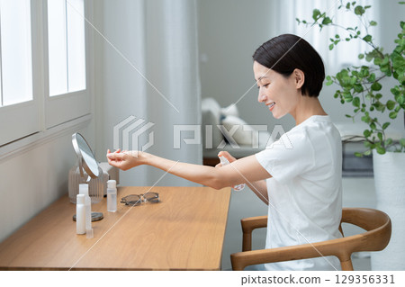 一位女士在手臂上塗抹防紫外線劑 一位女士在手臂上塗抹防紫外線劑 129356331