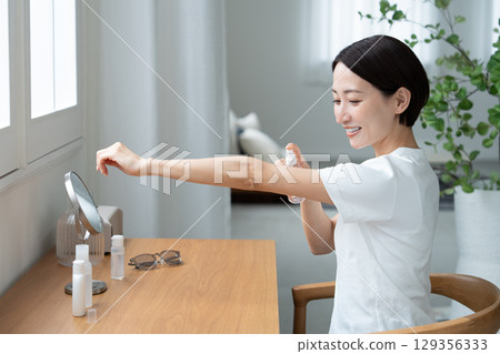 一位女士在手臂上塗抹防紫外線劑 一位女士在手臂上塗抹防紫外線劑 129356333