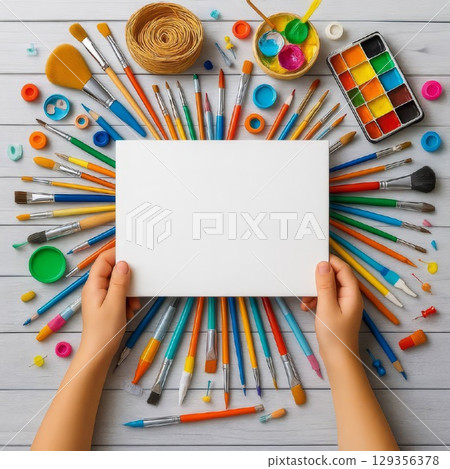 Blank canvas with colorful paintbrushes and art supplies. Flat lay on wooden table. Creative workspace for children or artists. Concept of imagination and artistic freedom. 129356378