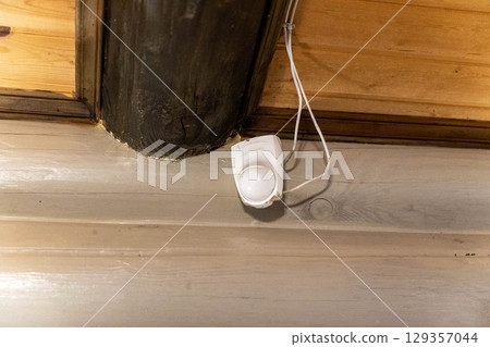 Motion sensor hanging on wooden ceiling providing security 129357044