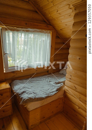 Cozy wooden cabin bedroom with unmade bed and natural light Cozy wooden cabin bedroom with unmade bed and natural light 129357050