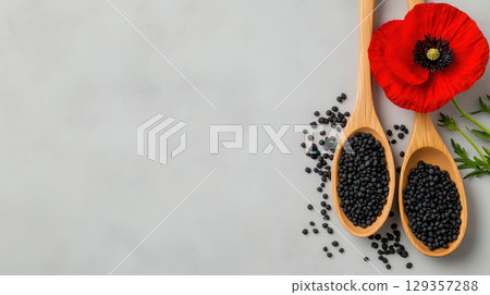 Wooden spoons with poppy seeds and red poppy flower on a grey background Wooden spoons with poppy seeds and red poppy flower on a grey background 129357288