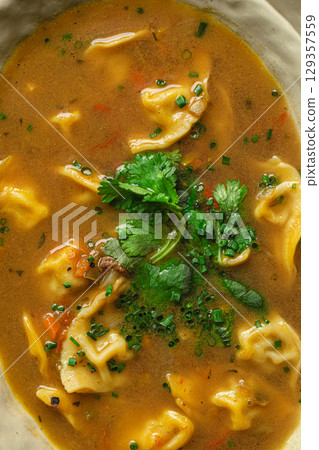 Bowl of soup with dumplings and fresh herbs 129357559