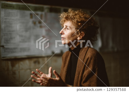 Mid-aged woman with natural curls speaking to a small group in a community center, generated AI 129357588