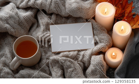 Greeting card on the background of an autumn scene with cinnamon, flowers, tea and candles 129358135