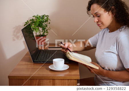 Woman Working Remotely in a Cozy Home Office Setting 129358822