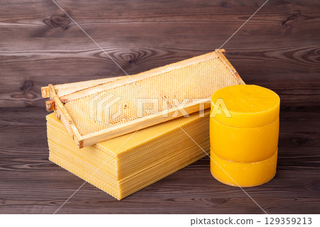 Beeswax in sheets and disks, frame from the hive on top. Beekeeping concept, natural beeswax on the table Beeswax in sheets and disks, frame from the hive on top. Beekeeping concept, natural beeswax on the table 129359213