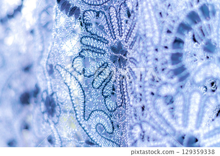 Detailed image capturing the intricate craftsmanship of a lace pattern with floral design in shades of blue 129359338
