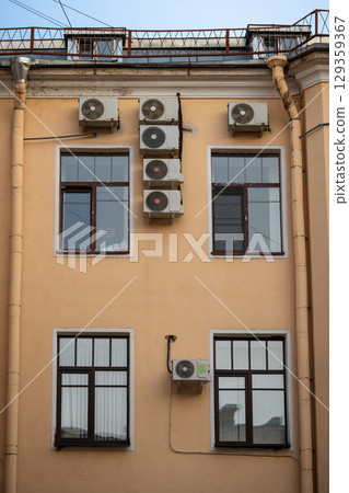 Facade of building with many air conditioners on windows in southern hot country. Escape from heat 129359367