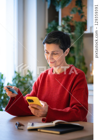 Relaxed smiling make online purchases with debit card with smartphone. Online shopping, ecommerce 129359391