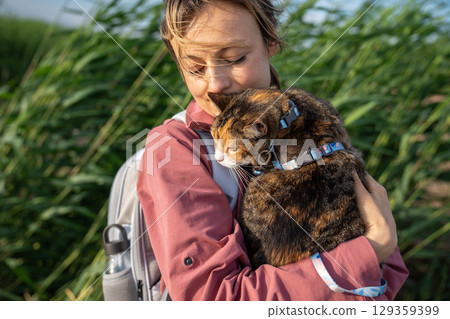 Sullen intrigued cat observing surroundings on walk clinging to woman in nature. Scared pet explorer Sullen intrigued cat observing surroundings on walk clinging to woman in nature. Scared pet explorer 129359399