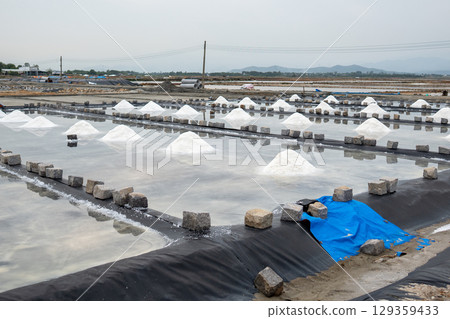 Salt mounds form in evaporation pools near Asian village using natural sun drying in rural area 129359433