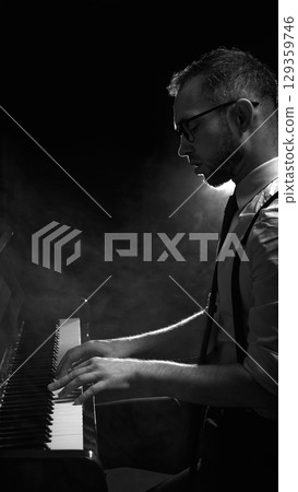Man playing piano in silhouette with backlight and atmospheric smoke 129359746