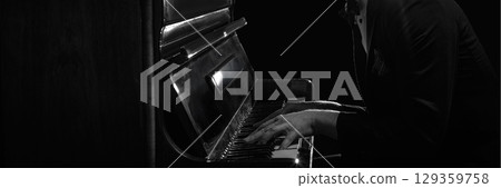 Close-up of man in suit playing piano with focus on hands in black and white lighting. Banner Close-up of man in suit playing piano with focus on hands in black and white lighting. Banner 129359758