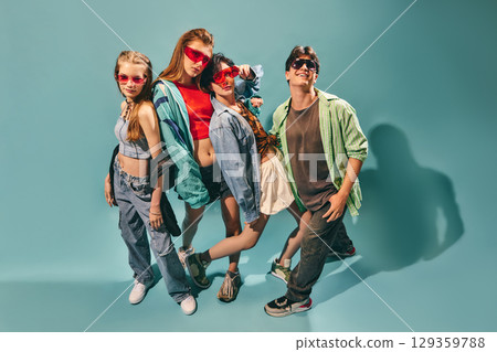 Trendy young friends smiling and posing in casual streetwear against blue background 129359788