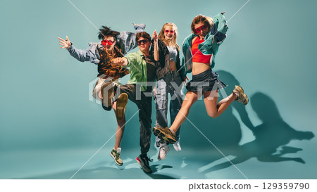 Energetic group of young people jumping in colorful streetwear on turquoise studio background 129359790